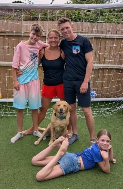 Andy Thompson and his family with their dog in front of a football goal at home